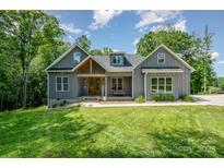 Charming gray farmhouse-style home with a welcoming front porch, lush green lawn, and mature trees at 5215 Star Magnolia Ct, Clover, SC 29710