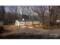 Charming single-story home featuring a white brick exterior, gravel driveway, and a well-manicured front yard at 5520 Chestnut Dr, Hickory, NC 28602