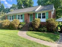 Charming brick home featuring a well-manicured lawn, vibrant green shutters, and a welcoming front entrance at 5806 Whitingham Dr, Charlotte, NC 28215