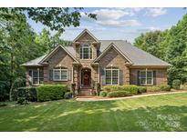 Beautiful brick home with manicured lawn, mature trees, and a welcoming front porch at 5812 Morgan Park Dr, Monroe, NC 28110