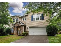 Charming two-story home featuring stone accents, blue shutters, well-maintained landscaping, and an attached two-car garage at 6914 Evanton Loch Rd, Charlotte, NC 28278
