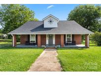 Charming brick home featuring a covered porch, black shutters and a beautifully maintained lawn at 85 Ruritan Park Rd, Stony Point, NC 28678