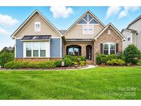 Beautiful two-story home featuring a well-manicured lawn, stone accents, and inviting front porch at 10903 Skymont Dr, Huntersville, NC 28078