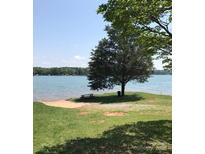 Stunning lake view with a sandy beach, picnic table, and shady tree perfect for relaxing by the water at 134 Crystal Cir, Mooresville, NC 28117