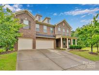 Charming brick home featuring a three-car garage, manicured lawn, and inviting front porch at 1355 Cilantro Ct, Fort Mill, SC 29708