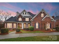 Stunning brick home featuring lush landscaping and a welcoming covered front porch at 201 Limerick Dr, Matthews, NC 28104
