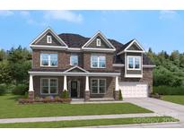 Charming two-story brick home with a well-manicured lawn, elegant dormers, and attached garage at 203 Balboa St, Matthews, NC 28104