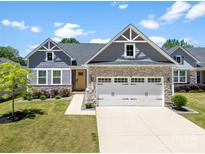 Charming home featuring stone accents, a two-car garage, and a well-manicured lawn on a sunny day at 2217 Goldwood Dr, Charlotte, NC 28215
