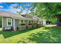 Charming home featuring well-kept lawn, stone accents, flower boxes, and a relaxing bench under a shade tree at 454 N Eastway Dr, Troutman, NC 28166