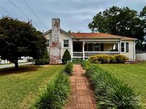 Charming home with a brick chimney, a covered front porch, and manicured landscaping along the walkway at 522 W Congress St, Lincolnton, NC 28092