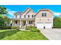 Inviting two-story home with a charming front porch, fountain, manicured lawn, and two-car garage at 7480 Katelyn Ct, Harrisburg, NC 28075