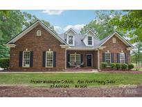 Charming brick home featuring dormer windows, black shutters, mature landscaping, and a welcoming front porch at 105 Prairie Rose Ct, Waxhaw, NC 28173