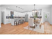 Modern kitchen with white cabinetry, stainless steel appliances, a kitchen island, and an adjacent dining area at 106 Arbor Dr, Waxhaw, NC 28173