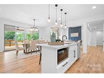 Bright open kitchen featuring an island with seating, modern lighting, and stainless steel appliances at 106 Arbor Dr, Waxhaw, NC 28173