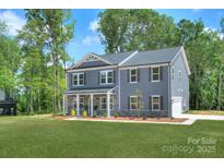 Charming two-story home with a gray exterior, covered porch and well-manicured lawn, set against a backdrop of lush trees at 2000 Plainfield Dr, Bessemer City, NC 28016