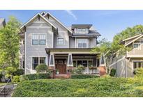 Charming home featuring a covered front porch, brick accents, and professionally landscaped front yard at 2221 Kenmore Ave, Charlotte, NC 28204