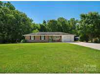 Charming brick home featuring a well-manicured lawn, mature trees, and an attached garage, offering classic curb appeal at 2451 Robert H Kirk Rd, Lancaster, SC 29720