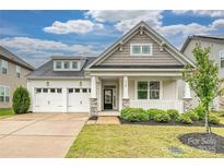 Charming home with a two-car garage, inviting front porch, manicured lawn, and appealing architectural details at 2760 Berkhamstead Cir, Concord, NC 28027