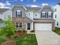Charming two-story home with a stone facade, well-manicured lawn, and an attached two-car garage at 300 Kennerly Center Dr, Mooresville, NC 28115
