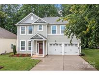 Charming two-story home with a well-manicured lawn and a two-car garage at 308 Planters Way, Mount Holly, NC 28120