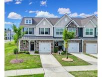 Charming townhome featuring a well-manicured lawn and attached garages, offering a blend of comfort and curb appeal at 4003 Rothwood Ln, Harrisburg, NC 28075