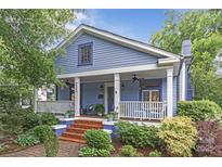 Charming blue two-story home with a inviting front porch, well-maintained garden, and a brick walkway at 413 E Worthington Ave, Charlotte, NC 28203