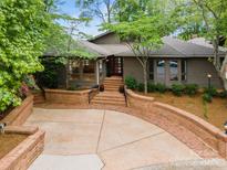 Inviting exterior showcases brick accents, mature trees, and a concrete driveway leading to the entrance at 449 Windward Dr, Davidson, NC 28036