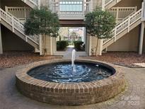 Inviting courtyard featuring a brick fountain, lush landscaping, and access to staircases in a charming community at 5003 Sharon Rd # Q, Charlotte, NC 28210