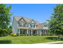 Charming two-story home featuring stone accents, lush landscaping, and a well-manicured lawn under a clear blue sky at 6535 Bridgemoor Dr, Indian Trail, NC 28079