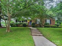Charming brick home with a well-manicured lawn and mature trees creating a welcoming curb appeal at 6734 Knollgate Dr, Charlotte, NC 28212