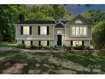 Charming two-story home with light yellow siding, black shutters, and manicured front yard at 7018 Rollingridge Dr, Charlotte, NC 28211