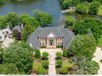 Stunning waterfront estate boasts manicured landscaping and a stately facade with lake views at 8721 Lake Challis Ln, Charlotte, NC 28226