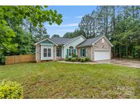 Charming single-story home featuring a brick facade, lush lawn, and attached two car garage at 105 Stumpy Creek Rd, Mooresville, NC 28117