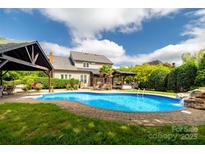 Backyard oasis featuring a pool, covered patio, and manicured landscaping perfect for outdoor entertaining at 1522 12Th Fairway Nw Dr, Concord, NC 28027