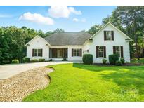 Charming single Gathering home showcasing lush green lawn, complemented by the elegance of white brick and dark shutters at 167 Logan Crossing Dr, Davidson, NC 28036