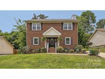 Charming two-story red brick home featuring a well-manicured lawn and inviting front porch, creating a warm and welcoming curb appeal at 6221 Round Hill Rd, Charlotte, NC 28211