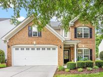 Charming two-story brick home featuring a two-car garage, manicured lawn, and beautifully landscaped front yard at 6619 Hermsley Rd, Charlotte, NC 28278