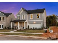 Charming two-story home with gray siding, a front porch, and an attached two-car garage at 7101 Short Stirrup Ln, Mint Hill, NC 28227
