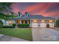 Charming brick home featuring a three-car garage, dormer windows, and professionally landscaped yard at 8725 Soaring Eagle Ln, Waxhaw, NC 28173