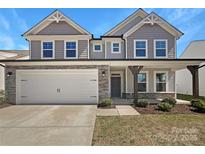 Charming two-story home featuring a two-car garage and covered entryway with stone and gray shingle exterior accents at 163 W Heart Pine Ln, Statesville, NC 28677
