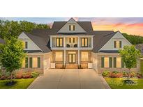 Stunning brick home boasts a two-story entryway with a balcony, lush landscaping, and an expansive driveway at 1702 Batson Creek Ln, Weddington, NC 28104