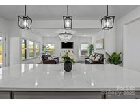 Modern open-concept design showcasing the kitchen island with quartz countertops and pendant lighting overlooking the living room at 3127 Pinehills Way, Mount Holly, NC 28120