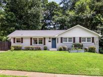 Charming one-story home with a well-maintained lawn, a blue front door and wood shutters at 3530 Woodleaf Rd, Charlotte, NC 28205
