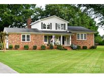 Charming two-story brick home features a covered front porch, manicured lawn, and mature trees at 7448 Forney Hill Rd, Denver, NC 28037