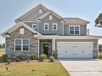 Beautiful two-story home with stone accents, gray siding, manicured lawn, and a two-car garage at 119 Tonbridge Way # Haf0033, Mooresville, NC 28115