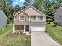 Charming two-story home featuring a stone facade, a covered front porch, and an attached two-car garage at 15203 Oldcorn Ln, Charlotte, NC 28262