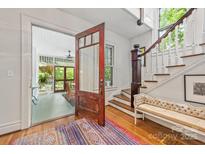 Inviting entryway with hardwood floors, open doorway to porch, stairway, and bench at 1801 E 8Th St, Charlotte, NC 28204