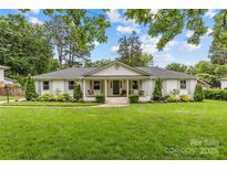 Charming ranch-style home with a manicured lawn, lush landscaping and inviting front porch swings at 227 Wingrave Dr, Charlotte, NC 28270
