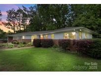 Charming single-story home with a brick accent wall and a well-manicured green lawn surrounded by lush trees at 2666 Providence Dr, Gastonia, NC 28052