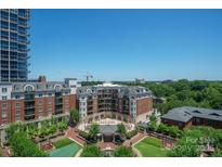 Expansive aerial view of a vibrant community featuring lush landscaping and elegant brick buildings with a city skyline backdrop at 300 W 5Th St # 812, Charlotte, NC 28202